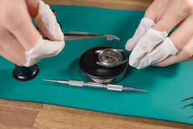 Profesyonel saatçi, çalışma tezgahındaki ince aletleri kullanarak dikkatli bir montaj ve mekanik saat hareketinin onarımına odaklanır..