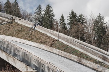 Zıplama tepesinde uçan kayakçı yarışmaya hazırlanmak için hız ve dengeye odaklanıyor..