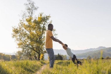 Baba ve çocuk dönüşleri doğadaki neşeli anları paylaşır, doğal ortamdaki sıcak bir akşamda kaldırır, kucaklar ve gülerler..