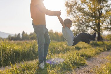 Baba ve çocuk doğada neşeli bir dönüş anı paylaşıyor, altın saat boyunca birlikte oynayıp gülüyorlar, güçlü aile bağlarını gösteriyorlar..