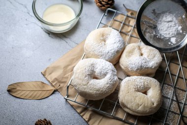Koyu arkaplanda pudra şekerli taze pişmiş çörekler. Kahvaltı konsepti, seçici odaklanma.