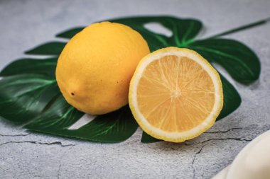 Taze organik sarı limon meyvesi dilimlenmiş yeşil yapraklar beyaz tabakta..