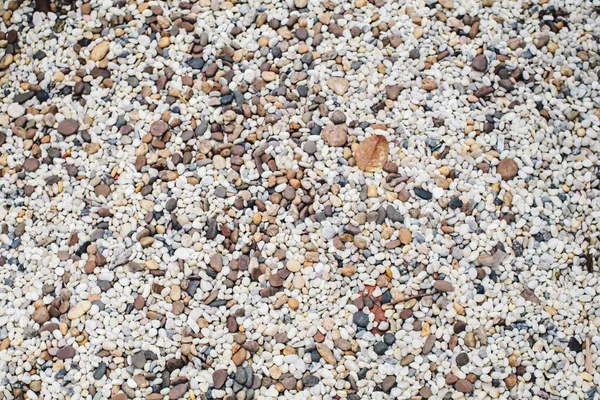 Abstract colorful mini granite crushed stones on ground texture background. Gray rubble construction rock pebble pattern.