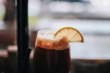 Buzlu americano kahvesi ve limon suyu dilimlenmiş ahşap bardak altlığı.. 