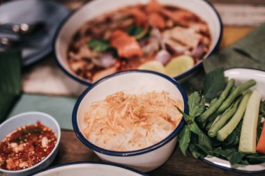 El yapımı çatal, pirinçli vermicelli ve üzerine kızarmış sarımsak serpilmiş papaya salatası gibi baharatlı yemeklerle servis edilir.