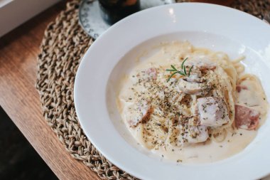 İtalyan makarnası - Pancetta, yumurta, parmesan peyniri ve krem soslu spagetti carbonara. Tahta masadaki beyaz tabakta. .