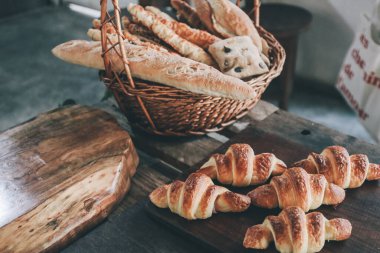 Taze baget ve kruvasan tezgahtaki hasır sepetin içinde duruyor. Lezzetli, kabuklu ekmek.