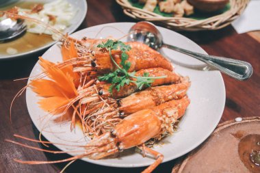 Tamarind soslu kızarmış karides. Popüler Tayland yemekleri. Bu tabakta sosla kaplı beş tane karides var. Sebzeler kişniş.