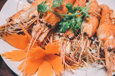 Tamarind soslu kızarmış karides. Popüler Tayland yemekleri. Bu tabakta sosla kaplı beş tane karides var. Sebzeler kişniş.