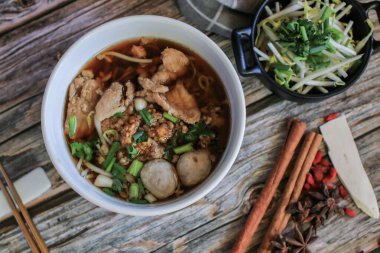 Domuz eti ve sebzeli erişte ve beş baharatlı, ahşap masa üstünde siyah çorba. Asya yemeği tarzı..