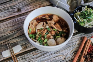 Domuz eti ve sebzeli erişte ve beş baharatlı, ahşap masa üstünde siyah çorba. Asya yemeği tarzı..