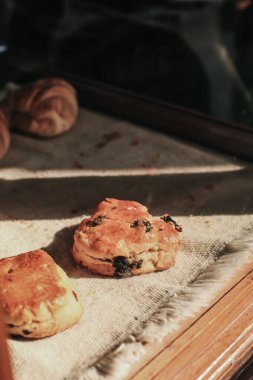 Frenk üzümlü çörekler. Nefis, lezzetli ev yapımı sultana çöreklerini kapayın. Ahşap masa üzerinde. Kahve dükkanında ışık ve gölge var..