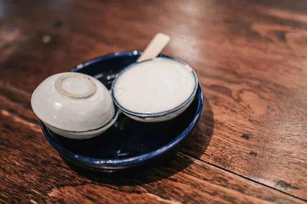 Coconut milk custard. Man eating Thai Coconut Milk Custard in small porcelain cup - Khanom Thuai (Thai dessert).