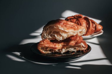 Croissants on a dark background in the morning light, sunlight shadow. Morning breakfast concept. Copy space. clipart