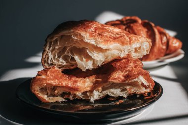 Sabah ışığında karanlık bir arka planda kruvasanlar, güneş ışığı gölgesi. Sabah kahvaltısı kavramı. Boşluğu kopyala.
