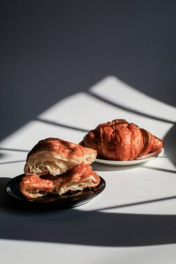 Sabah ışığında karanlık bir arka planda el yapımı kruvasan, güneş ışığı gölgesi. Sabah kahvaltısı kavramı. Boşluğu kopyala.