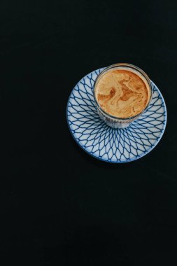 Koyu arkaplanda kirli latte kahve. Kahve dükkanı ve restoranda soğuk taze sütle karıştırılmış bir bardak espresso.