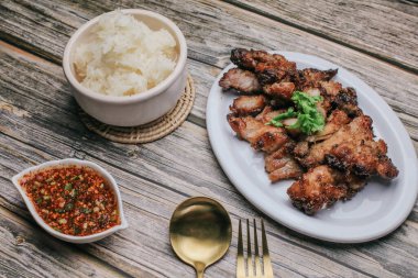 Baharatlı ızgara domuz boynu ve sade ahşap masada buharda pişmiş pilav, Tayland yemeği..