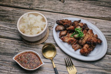 Baharatlı ızgara domuz boynu ve sade ahşap masada buharda pişmiş pilav, Tayland yemeği..