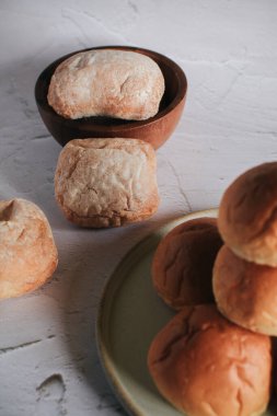 Taze pişmiş ekmek. Beyaz arka planda organik tam buğday somunları. Mini ekmek yığını. Fırın ekmeği ticareti..