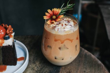 Şerbetli buzlu karamel latte kahve ve çiçekle süslenmiş krema. Eski moda kahve dükkanında kahve molası.