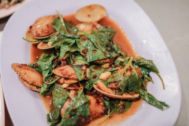 Kızarmış istiridyeleri beyaz tabakta kızartılmış acı biberle karıştır. Asya usulü..