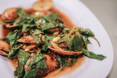 Kızarmış istiridyeleri beyaz tabakta kızartılmış acı biberle karıştır. Asya usulü..