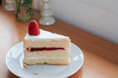 Strawberry and cream sponge cake on white plate. Dessert. On a wooden background. Top view. Free space for your text.
