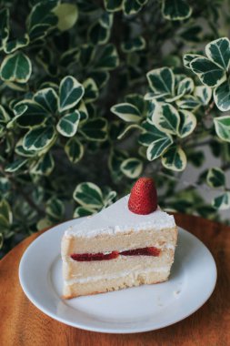 Strawberry and cream sponge cake on white plate. Dessert. On a wooden background. Top view. Free space for your text.