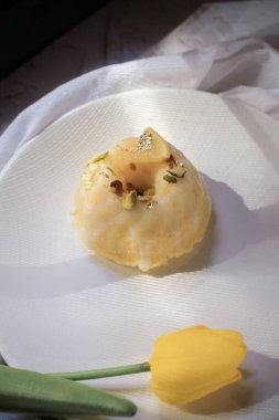 Sarı laleli limonlu pasta, klasik tarif, koyu arkaplanda beyaz seramik tabakla süslenmiş.