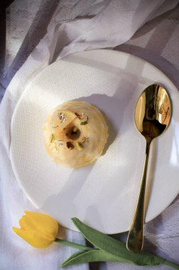 Sarı laleli limonlu pasta, klasik tarif, koyu arkaplanda beyaz seramik tabakla süslenmiş.