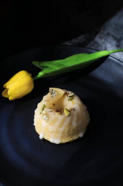 Koyu arkaplanda sarı lale yakınında güneş ışığı altında şekerli limonlu pasta. Turtayla geleneksel Amerikan mutfağı..