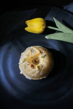 Koyu arkaplanda sarı lale yakınında güneş ışığı altında şekerli limonlu pasta. Turtayla geleneksel Amerikan mutfağı..