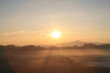 Dağ zirvesinde, sisli denizin üzerinde gün doğumu. Horizon, huzurlu manzaranın üzerine huzur dolu bir parıltı saçıyor..