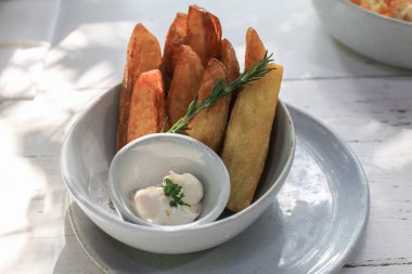 Biberiyeli kızarmış patates dilimleri ve beyaz kaseye batırma sosu. Lezzetli, gevrek atıştırmalıklar..