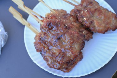 Möö ping, Tayland usulü ızgara bbq domuz şişleri ve beyaz tabakta yapışkan pirinç. Asya sokak yemekleri.