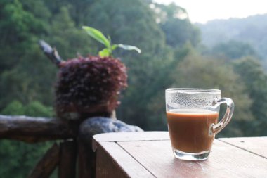 Orman manzaralı ahşap teras masasında sıcak kahve. Kahvaltı Tazeleniyor.