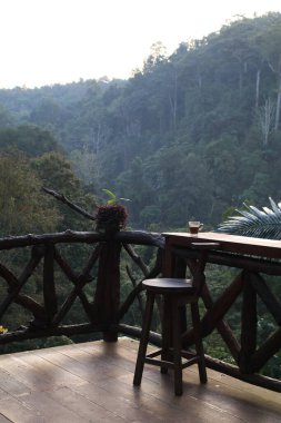 Tahta teras masaları ve güzel manzaralı bir orman manzarası olan bir sandalye. Doğada seyahat..