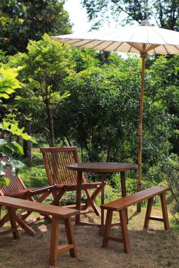 Boş ahşap sandalye ve şemsiyeli bir masa. Yaz ayları dışarıda dinlenir.