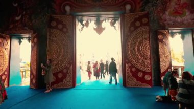 Yazı işleri. Tayland 'da Chiang rai' de Wat Rong Suea Ten (Mavi Tapınak) içinde bir grup turist ve ibadet eden insan