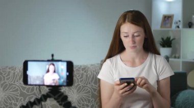 Bir kadın blogcu akıllı telefondaki bir şeyle şaşırır. Bir kadın blogcu kanalı için video çekiyor. Bir vlogger sosyal medya için bir video kaydeder. Aboneler için dişi bir vlogger akışı.