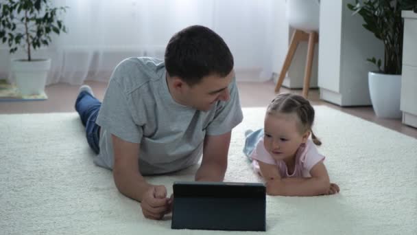 Dochter Vader Kijken Naar Iets Interessants Tablet Liggen Thuis Vloer — Stockvideo