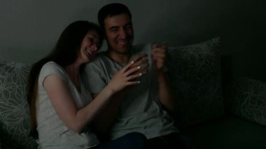 Mutlu adam ve kadın TV 'de komedi filmi izlerken gülüyorlar. Çekici çift televizyonda komik sinema izliyor. İnsanlar geceleri ya da akşamları televizyon karşısında vakit geçirirler..