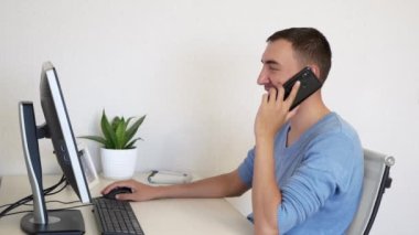 Yetişkin adam iş yerinde akıllı telefondan konuşuyor. Beyaz adam akıllı telefondan bir şeyler konuşuyor. Evde çalışan yakışıklı biri..