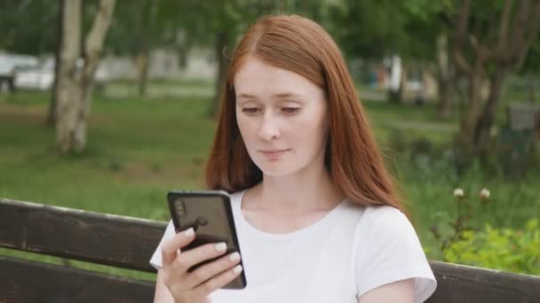Kızıl Saçlı Güzel Bir Kadın Parkta Bankta Oturur Akıllı Telefondan — Stok video
