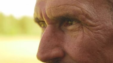 Bıyıklı olgun bir adama yakından bak. Yüzünde kırışıklıklar olan yaşlı adama yakından bak. Yetişkin birinin portresi.