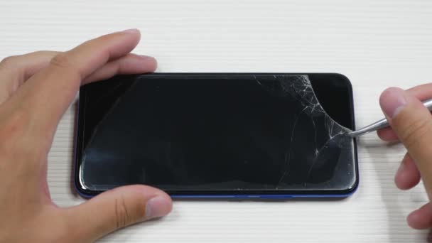 男はスマートフォンから壊れた保護ガラスを削除します 保護ガラスが割れているスマートフォンでビューを閉じます — ストック動画