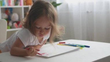 Küçük tatlı kız keçeli kalemlerle resim çiziyor. Evde yeni yürümeye başlayan bir kızın portresi.