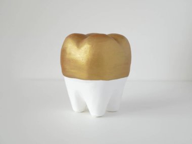 Beyaz masada izole edilmiş beyaz diş. Altın kapaklı, beyaz dişli domuz kumbarası. Diş bakımı kavramı.