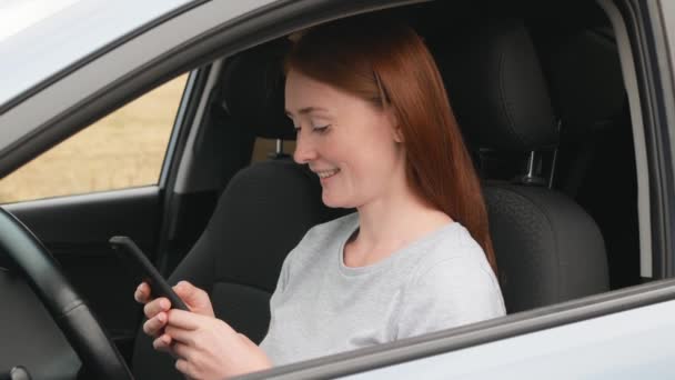 Mulher Bonita Com Cabelo Vermelho Usa Telefone Enquanto Senta Carro — Vídeo de Stock